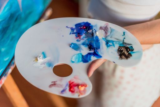 An artist using oil paints on a pallet with various colors