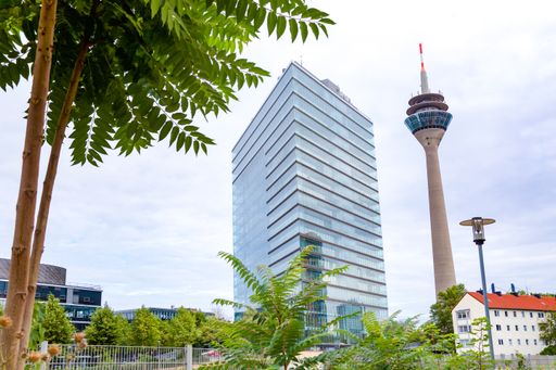 A low angle shot of a modern building surrounded by a garden in the middle of the city