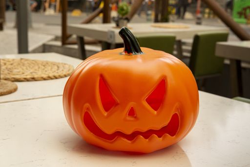 A closeup of a plastic pumpkin toy placed on a white table