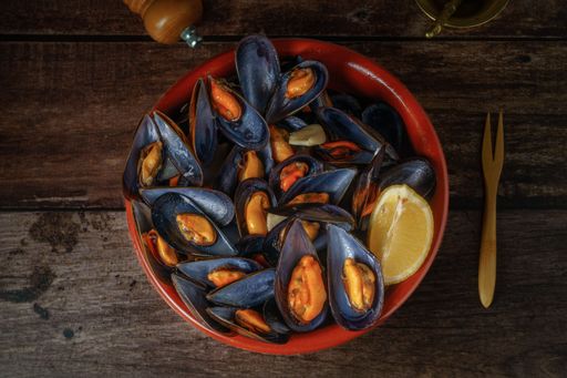 steamed mussels with lemon in clay pot with metal mortar and pepper shaker