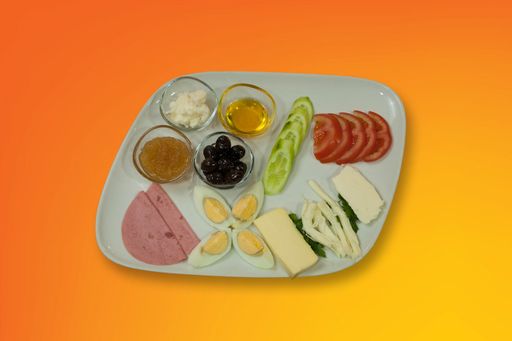 A high angle shot of a plate with cheese, egg, sausage, vegetables, olives and sauces on an orange surface