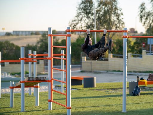 A young Hispanic man doing his workout in the morning exercising on a horizontal bar