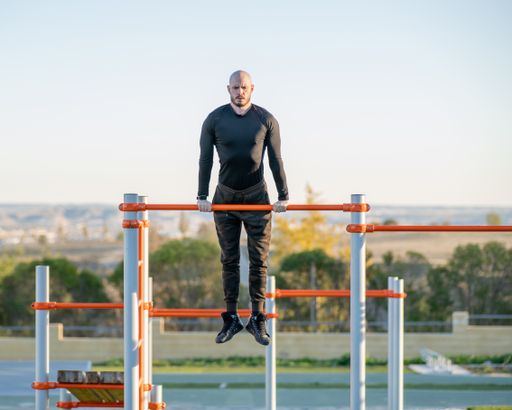 A young Hispanic man doing his workout in the morning exercising on a horizontal bar