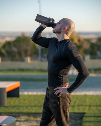 A young Hispanic man drinking water after working out in the sports ground
