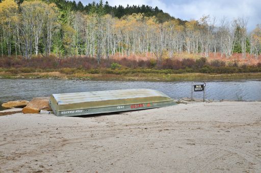 Old fishing boat named 'Fish Master' by a lake next to a 'No Fishing' sign; A funny contrast and reminder that some rules are Just made to be broken.
