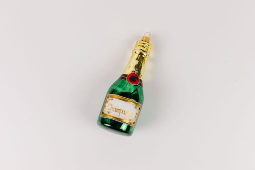 A single Christmas tree bauble in the shape of a green champagne bottle. The background is white.