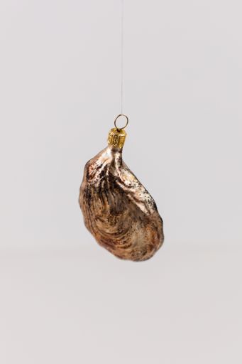 A vertical shot of a hanging bauble in the shape of an oyster shell on a white background