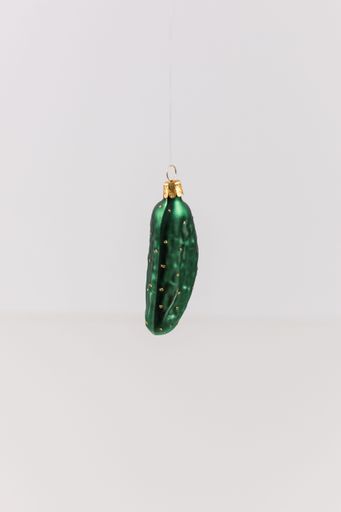 A vertical shot of a hanging bauble in the shape of a cucumber on a white background