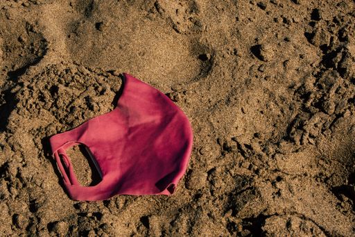A top view of a red face mask on a sandy beach