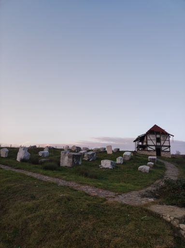 The vertical shot of old cemetery stones and an abandoned building before the blue skyline