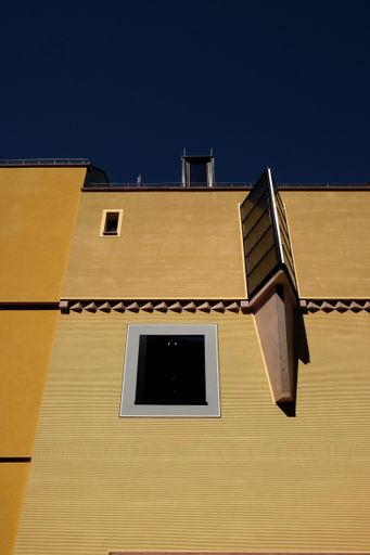 A low angle shot of a house with small windows under a dark blue sky background