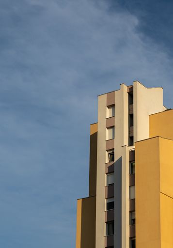 A vertical low angle shot of a concrete white and brown modern building under the cloudy sky
