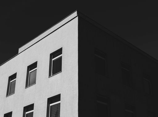 A greyscale low angle shot of a concrete building with a lot of windows under the dark sky