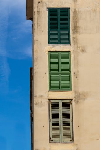 A vertical shot of an old concrete building with weathered windows with interesting textures