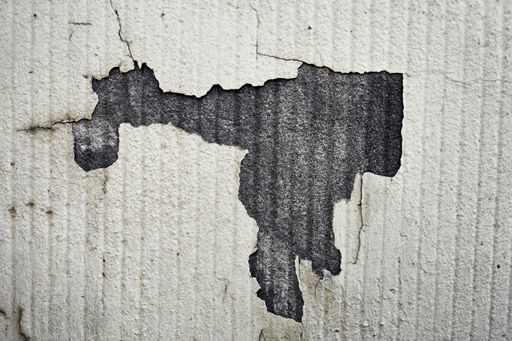 An old worn out white wall with part of the paint peeled off
