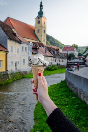 A vertical shot of a female hand holding ice cream in a waffle cone