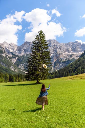 A vertical shot of a woman throwing her hat while standing on green grass