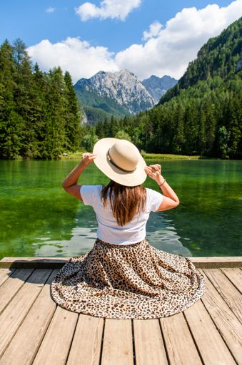 A back view of a young female enjoying view to calm lake in Slovenia