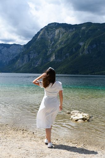 A happy white woman standing in front of the mountain chain at the Triglav National Park Bohinjsko, Slovenia