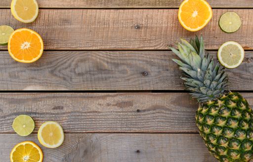 A top view of the collection of fresh lime, lemon, orange and  pineapple on wooden background