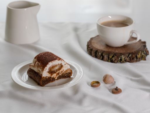 A closeup shot of a delicious creamy cake on the plate on a white fabric