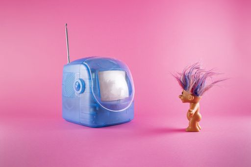 A closeup shot of funny toys and a toy TV on pink background