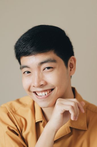 A closeup vertical portrait of a cute charming man tenderly touching his chin and smiling happily