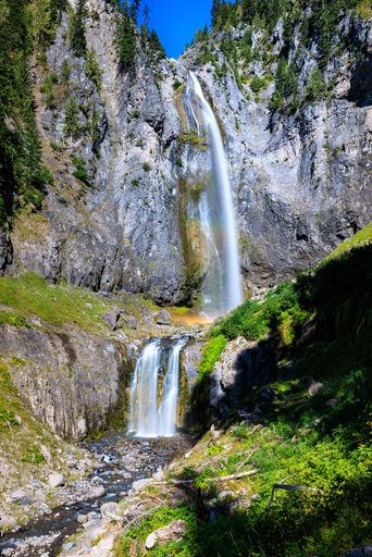 A vertical shot of beautiful waterfalls flowing down the rock on a sunny day