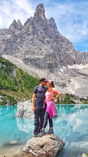 A couple kissing and standing on a rock against a mountain