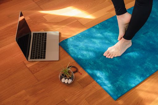 A closeup shot of female feet on yoga mat during an online class at home