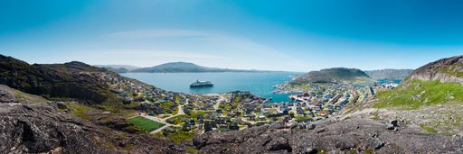 A panoramic shot of the coast at Greenland, Qaqortoq with a boat sailing in the sea