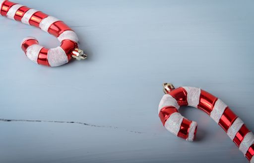 A closeup shot of candy cane shaped Christmas toys on a white cracked wooden surface with a copy space