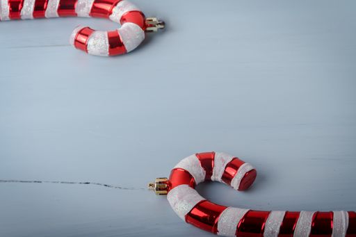 A closeup shot of candy cane shaped Christmas toys on a white cracked wooden surface with a copy space