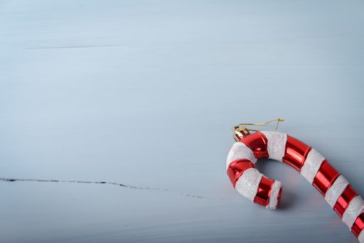 A closeup shot of a candy cane shaped Christmas toy on a white cracked wooden surface with a copy space