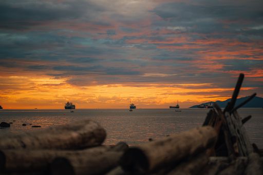 This is a sunset on a beach in Vancouver. Boats are far away.