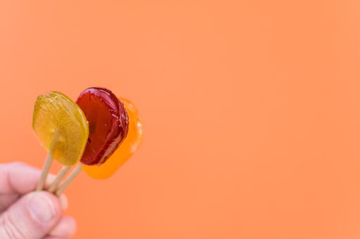 A closeup shot of a person holding lollipops on an isolated orange background