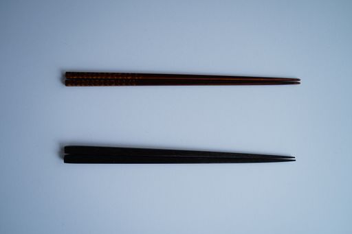 A high angle shot of two pairs of Japanese chopsticks on a grey background