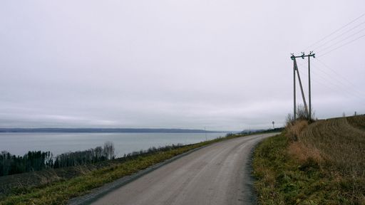 A beautiful shot of a road through a field near Lake Mjosa in Norway