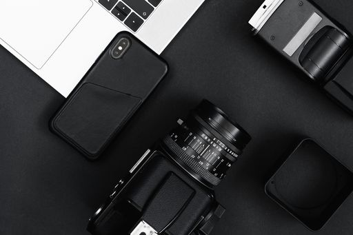 A top view of a camera and flash with a phone on a laptop on a dark surface