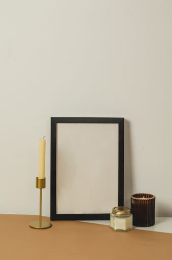A vertical shot of an Interior design of a living room with a black-framed poster mockup and candles