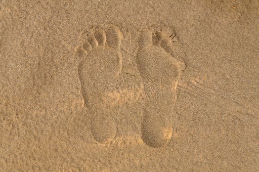 Human footsteps on white sand at beach