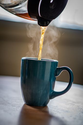 A man pouring tea into a mug from a teapot