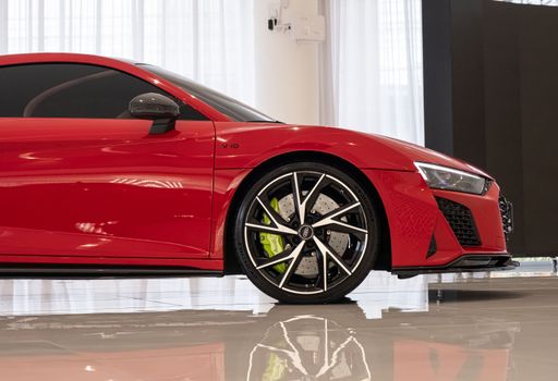 A side view of shiny red Audi R8 in the showroom, white background