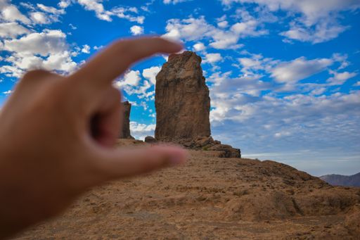 A selective focus shot of the Roque Nublo volcanic rock through a person's fingers