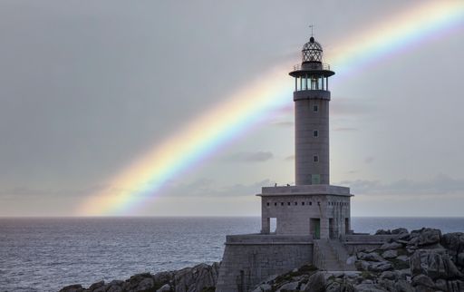 A beautiful shot of the Punta Nariga lighthouse, Galicia, Spain with a rainbow in backgroun