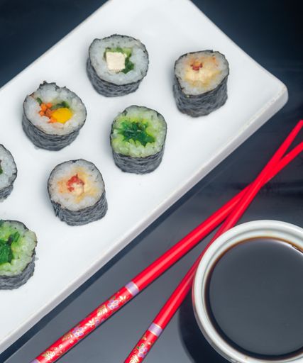A top view of delicious sushis on a plate with chopsticks and soy sauce on the table