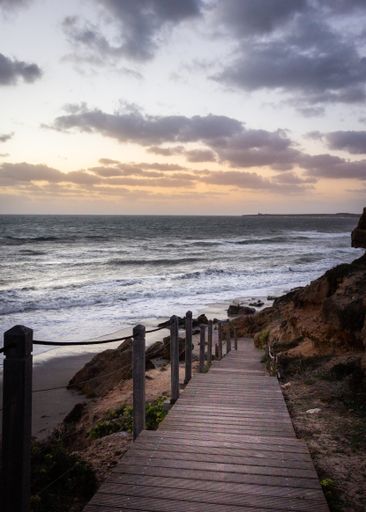 A vertical shot of wooden stairs into the sea during sunset in Italy