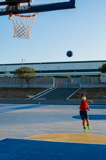 A vertical shot of a boy playing basketball wearing a sanitary mask-concept of the new normal