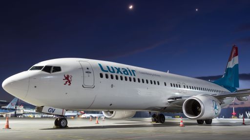 A Boeing 737-800 from Luxair parked on an airport ramp in the evening