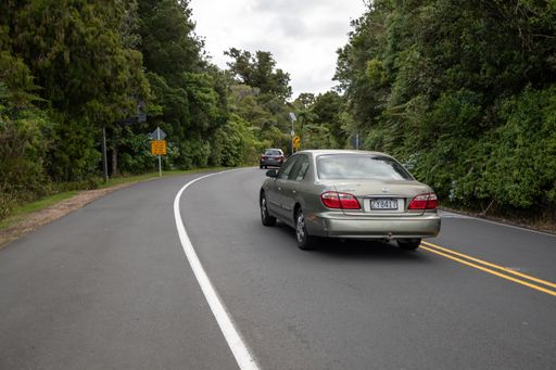 Auckland / New Zealand - January 10 2020: View of car driving on straight hilly road through Waitakere Ranges forest towards Piha village